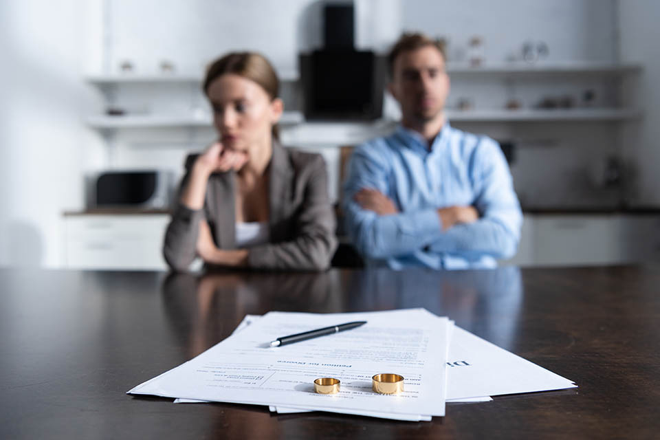 Selektive Fokussierung eines Paares, das mit Scheidungsdokumenten am Tisch sitzt